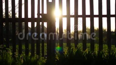 日出时太阳光束在木栅栏上耀斑.